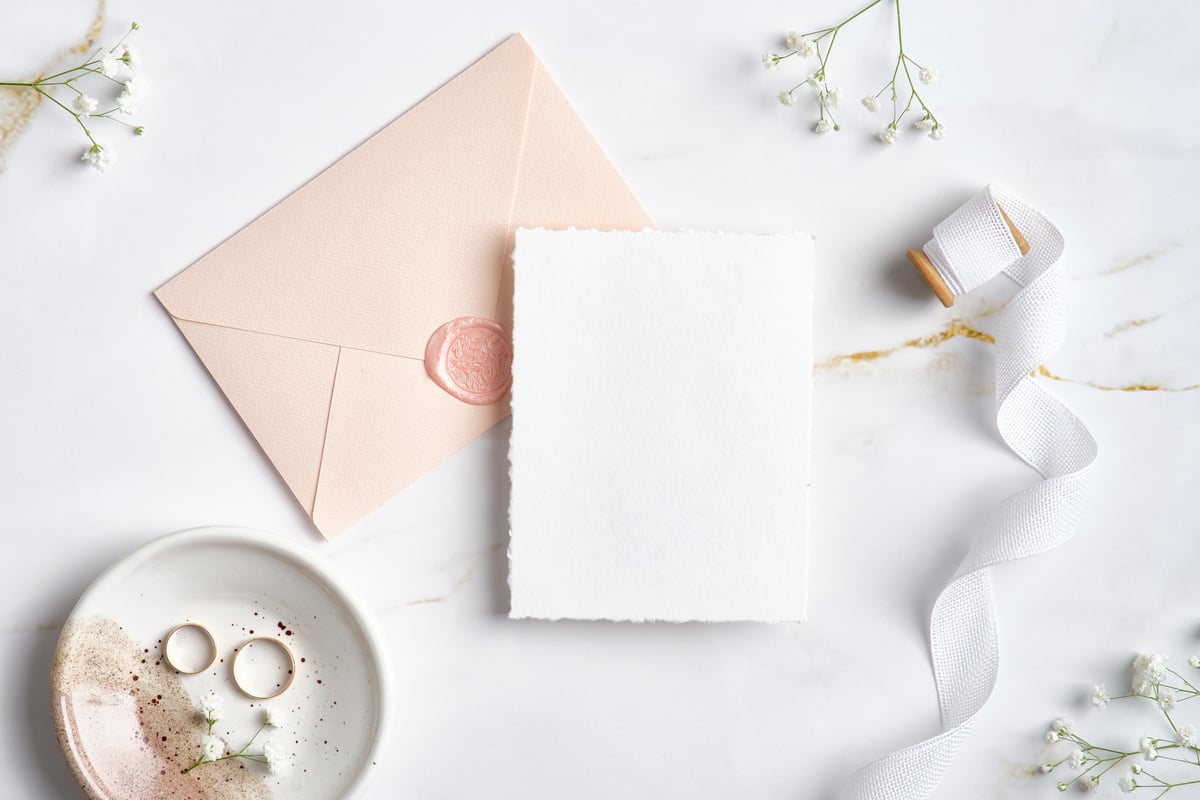 Elegant Wedding Stationery Set. Flat Lay Wedding Invitation Card Template, Pastel Pink Envelope, Silk Ribbon, Golden Rings, Flowers on Marble Desk.